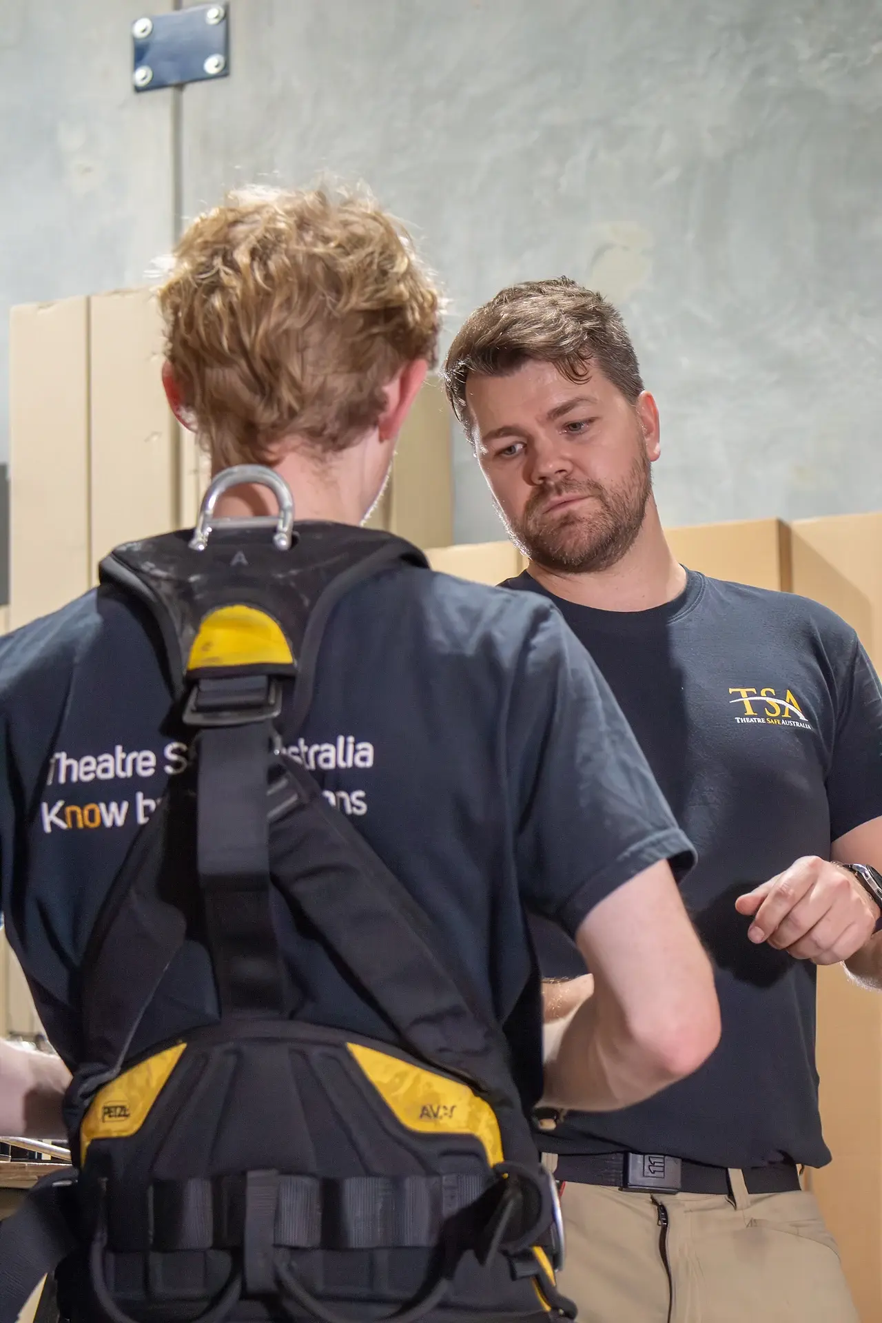 A TSA inspector checking the fit of a full-body harness on a colleague
