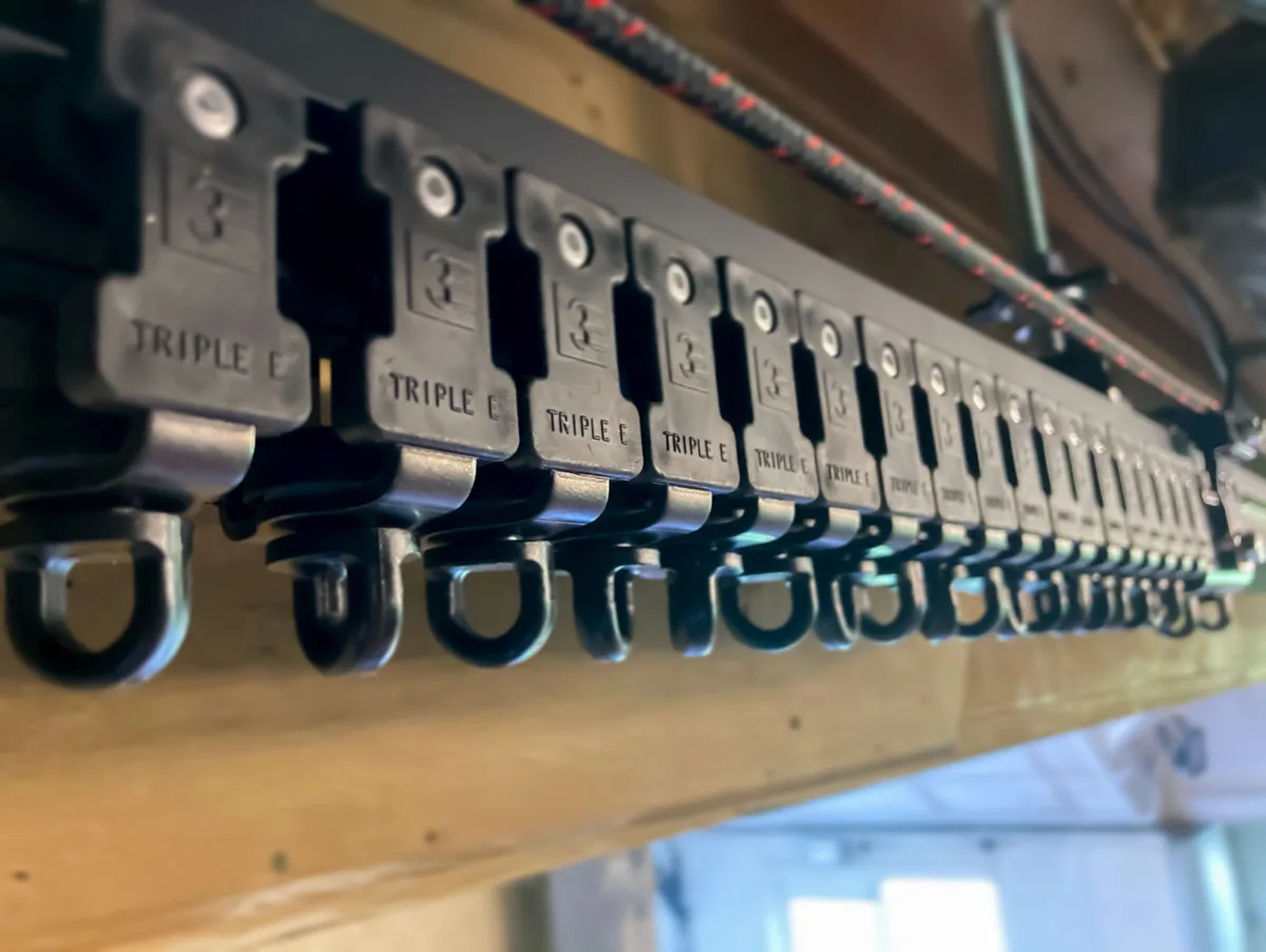 A row of curtain track runners with swivel eyelets on a track under a timber beam