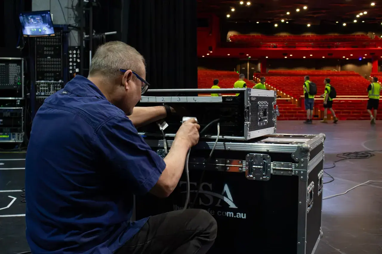 Rated overhead rigging carrying a performer-flying load, with marked clamps and secondary safety bonds on a stage rig.