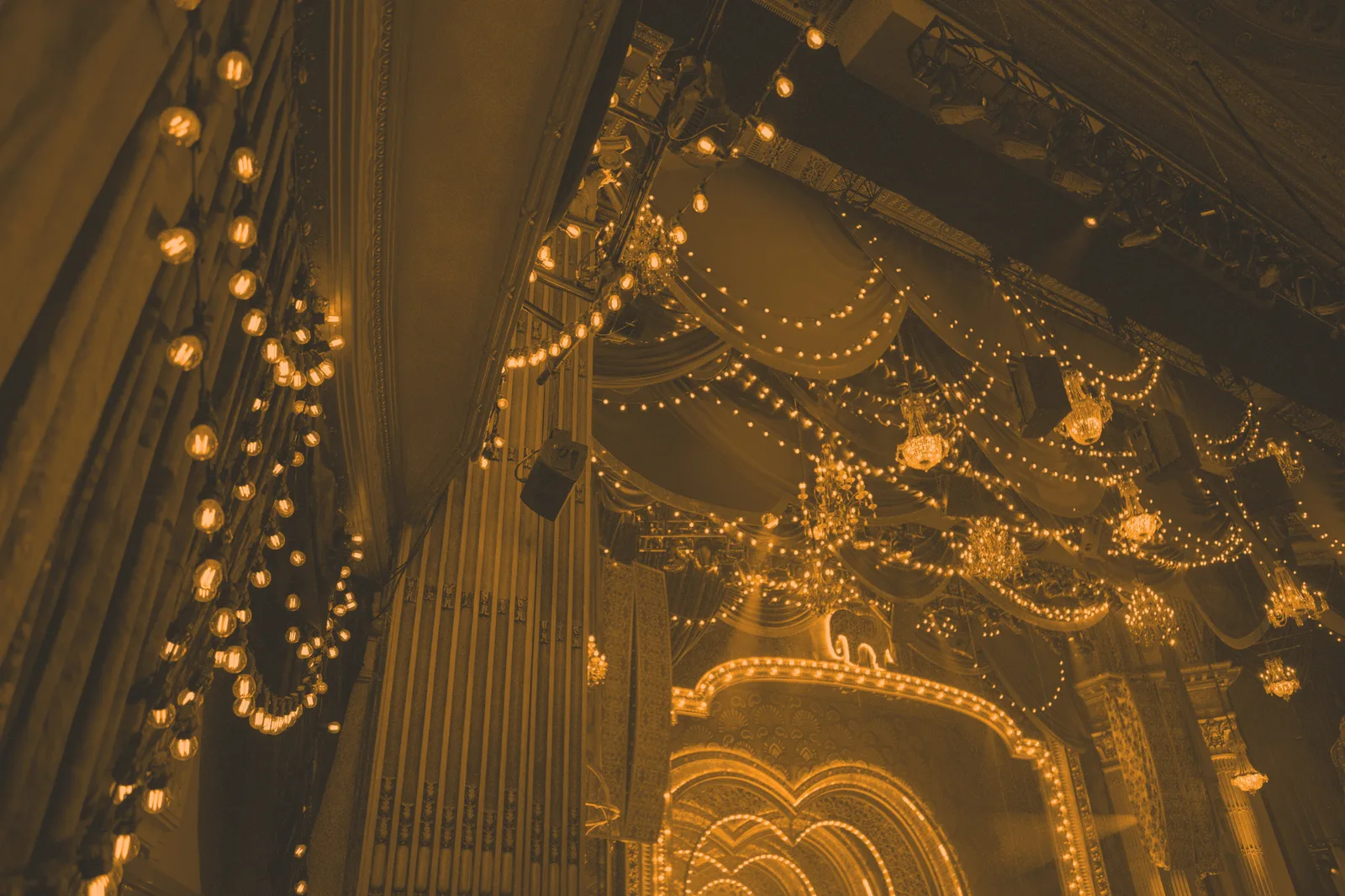 Ornate theatre proscenium dressed with a festoon house curtain and strings of lights