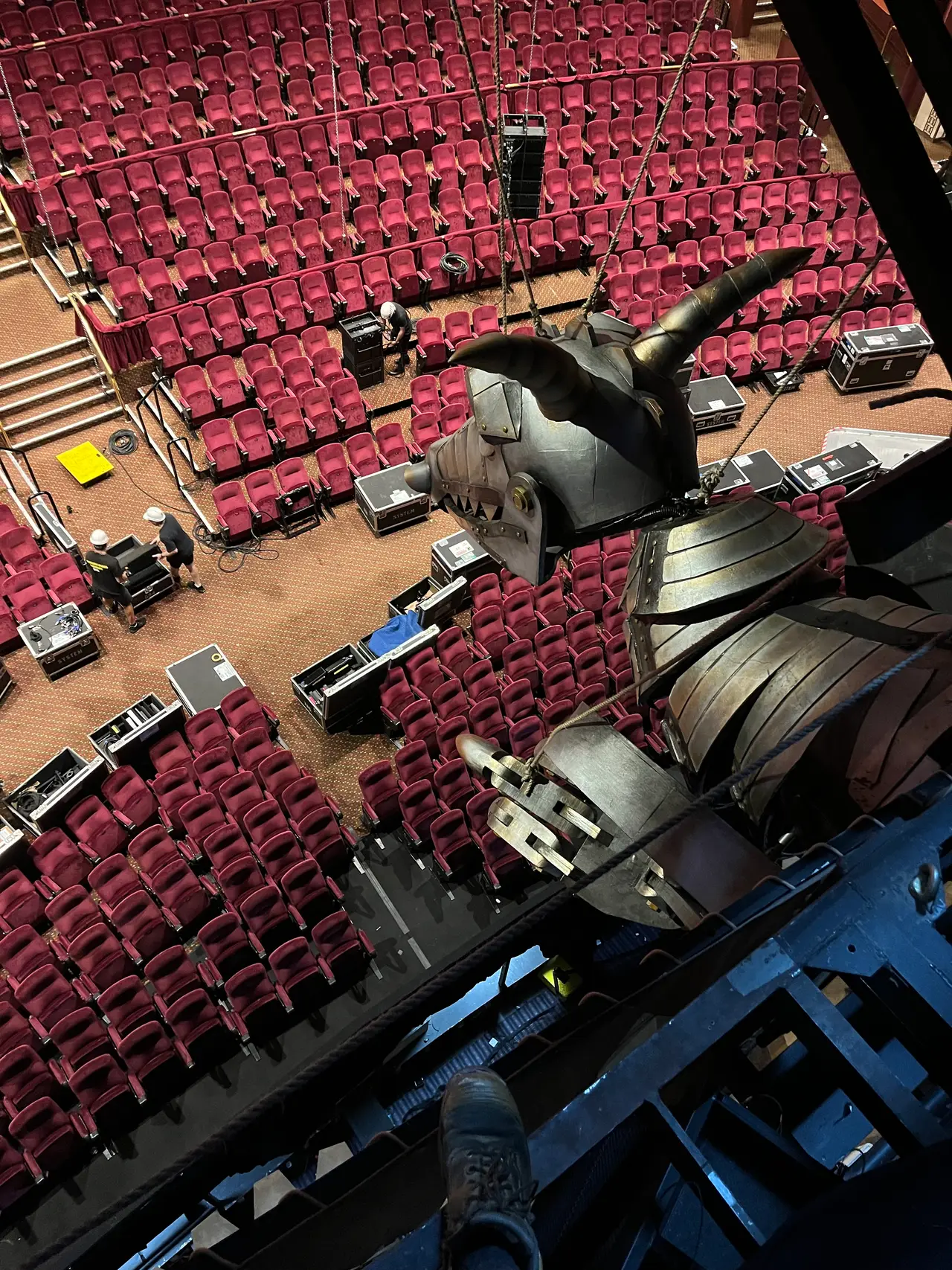 A flown dragon prop rig seen from above, hung over the auditorium at Wicked in Perth.