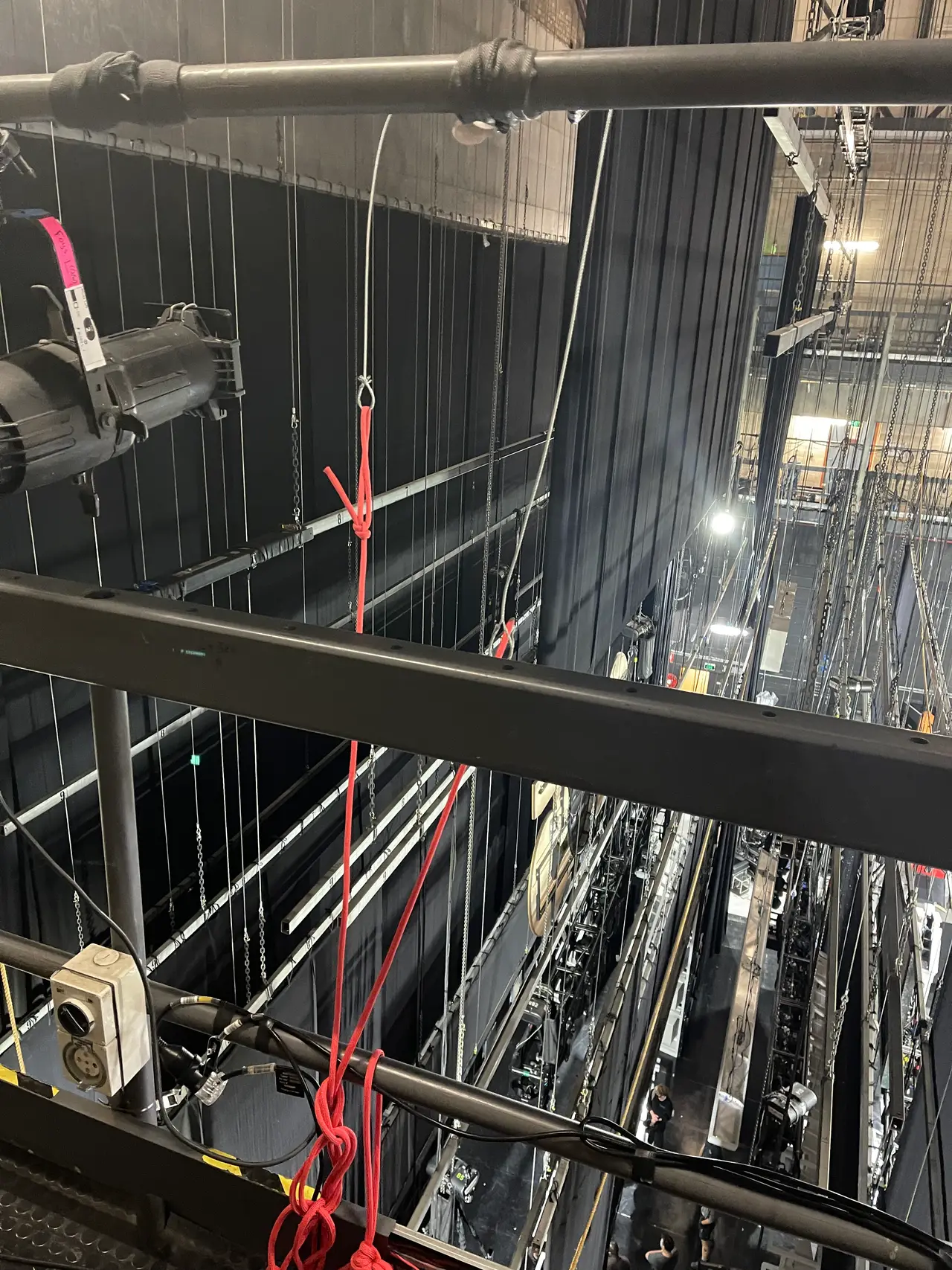 A fly tower catwalk with a red rope in the foreground, looking down over the stage grid.