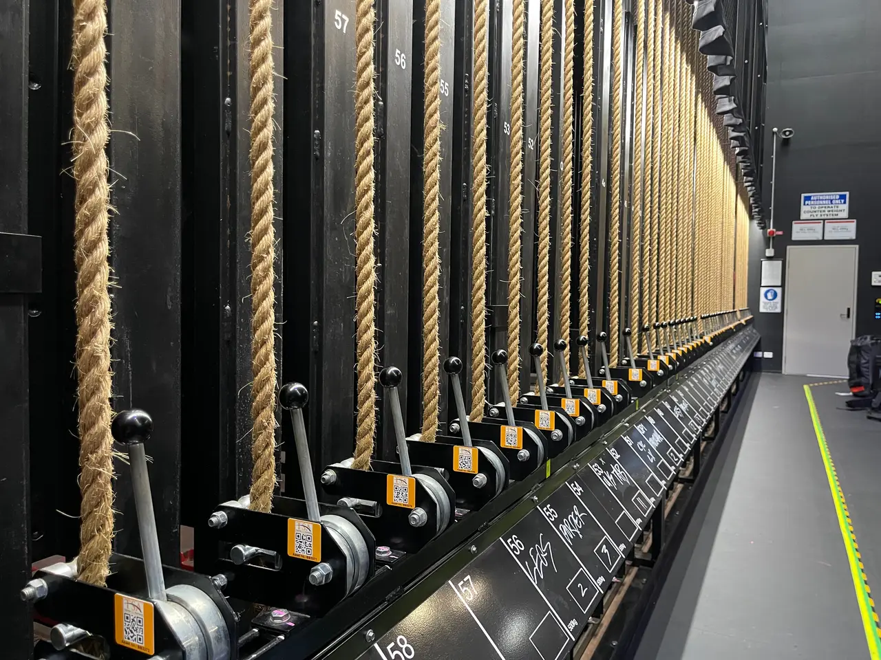 A counterweight rope-lock rail with numbered lines and safety signage.