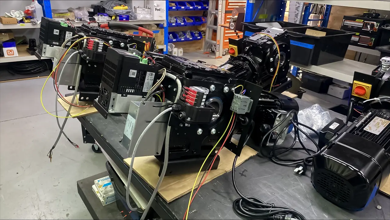A hoist drive assembly with drives, motor and wiring laid out on a workshop bench.