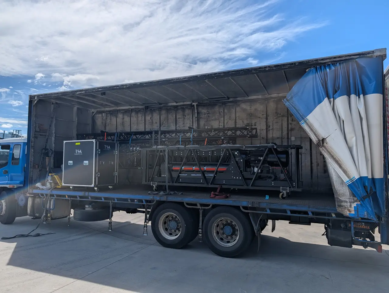 Large winch beam and truss assembly loaded on a flatbed truck, TSA flight case alongside