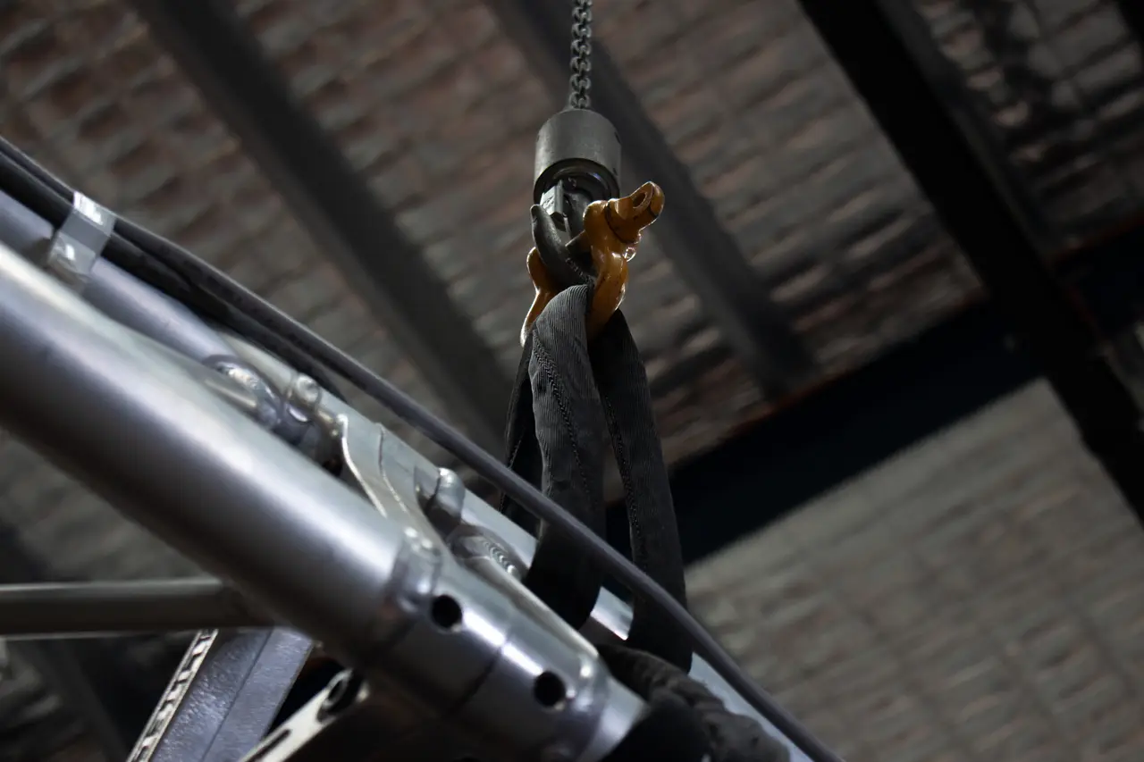 Soft steel sling attached to an orange hook on rigging truss