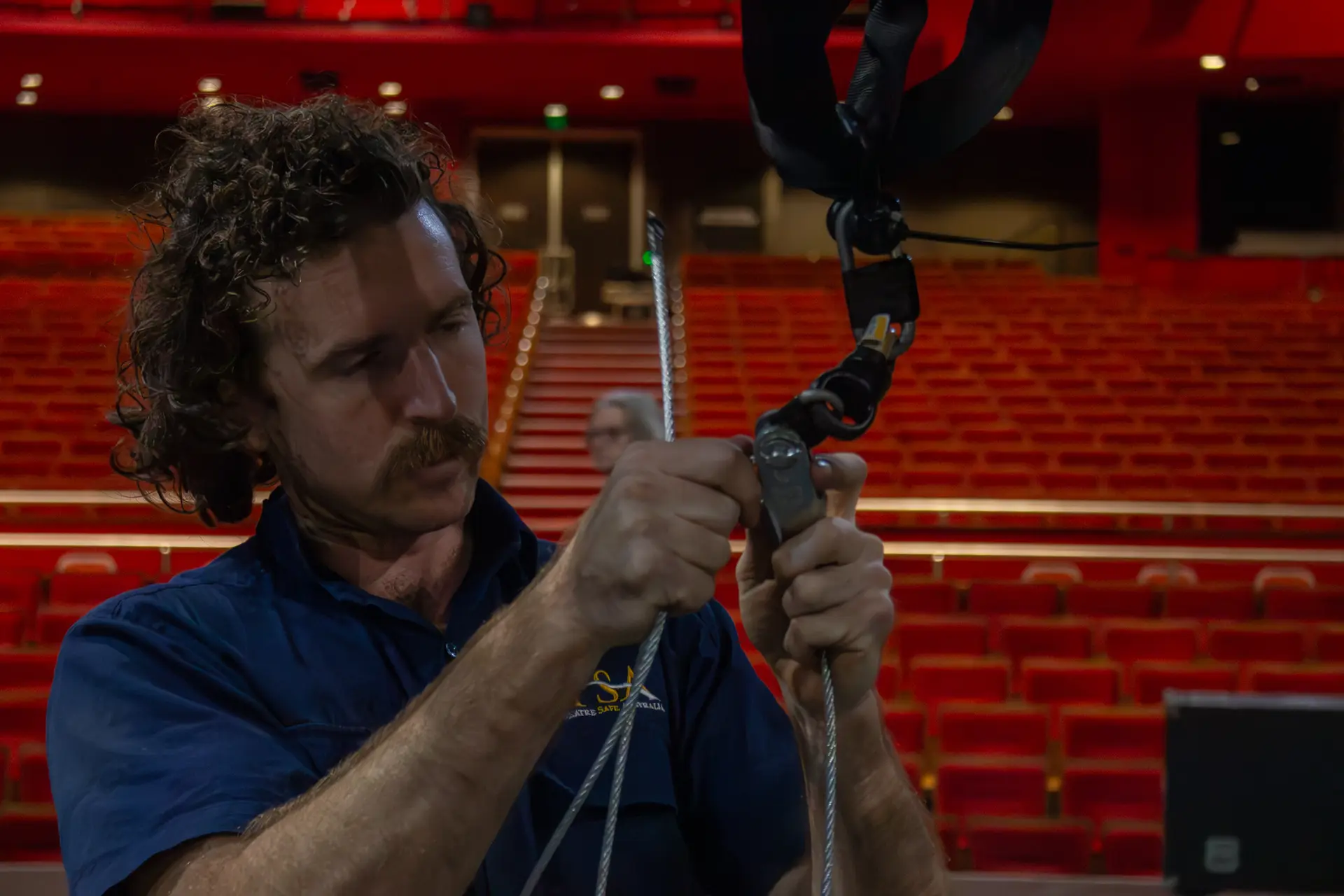 TSA crew member terminating a wire rope in a theatre auditorium