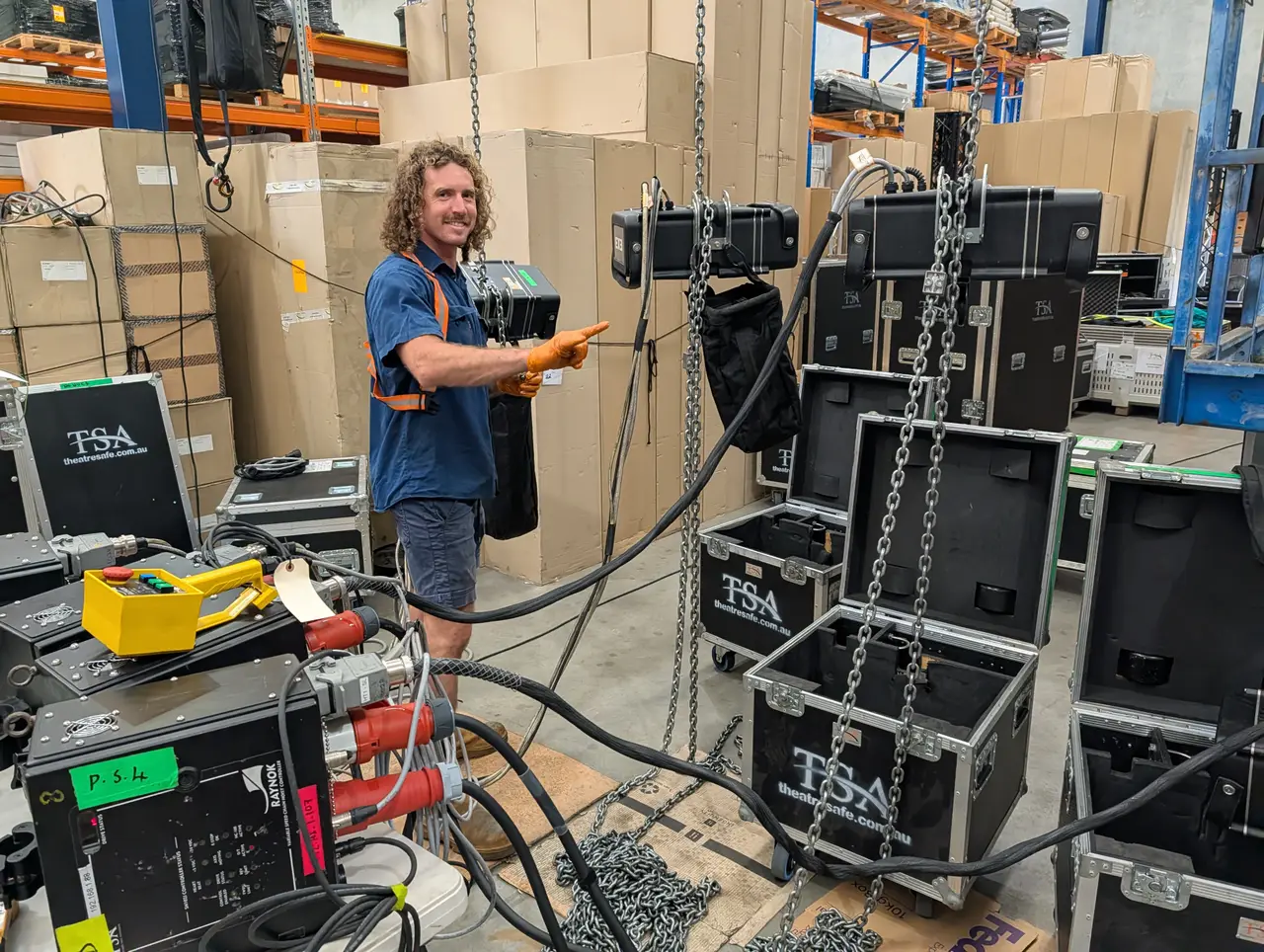 TSA technician pointing at chain hoists suspended in the warehouse for testing
