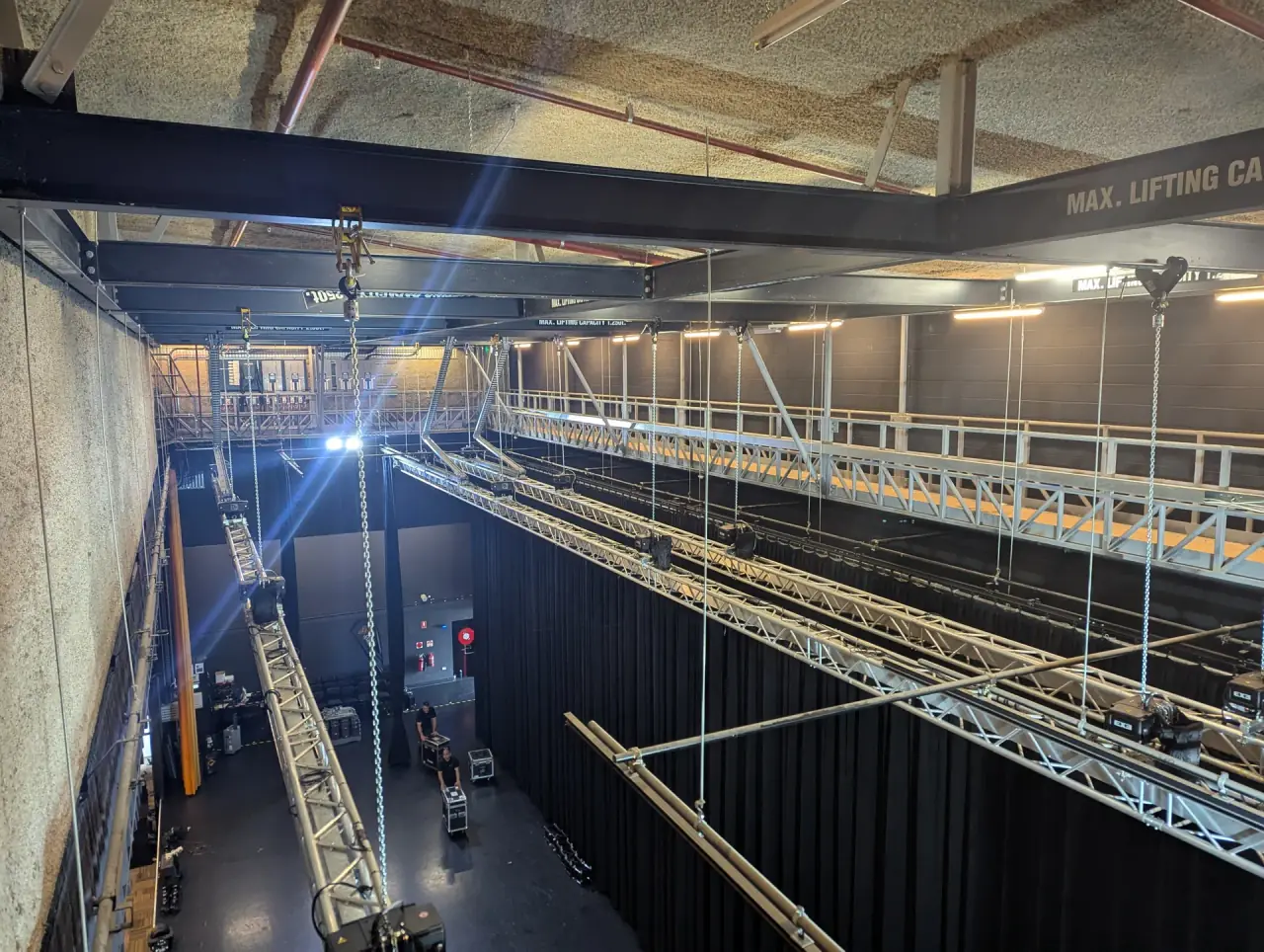 Truss and hoists run along the fly tower catwalk above the stage.