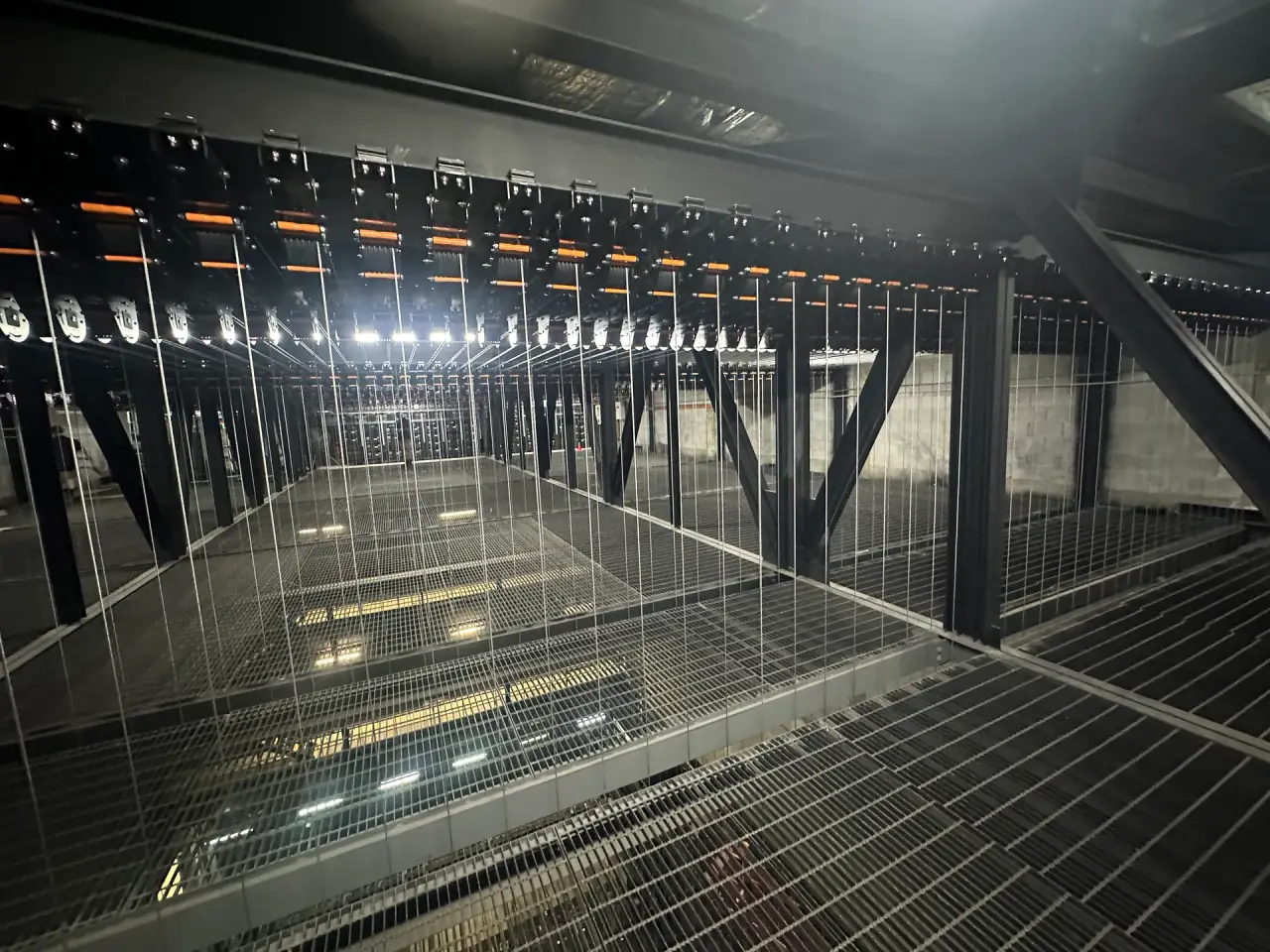 Looking along the fly tower grid catwalk, with wire ropes dropping from the loft block array.