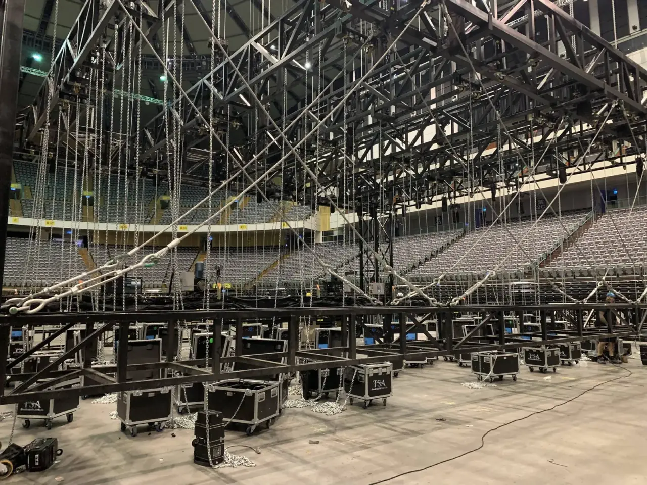 Wide shot of a chain hoist truss rig above stacked TSA road cases in an arena bowl