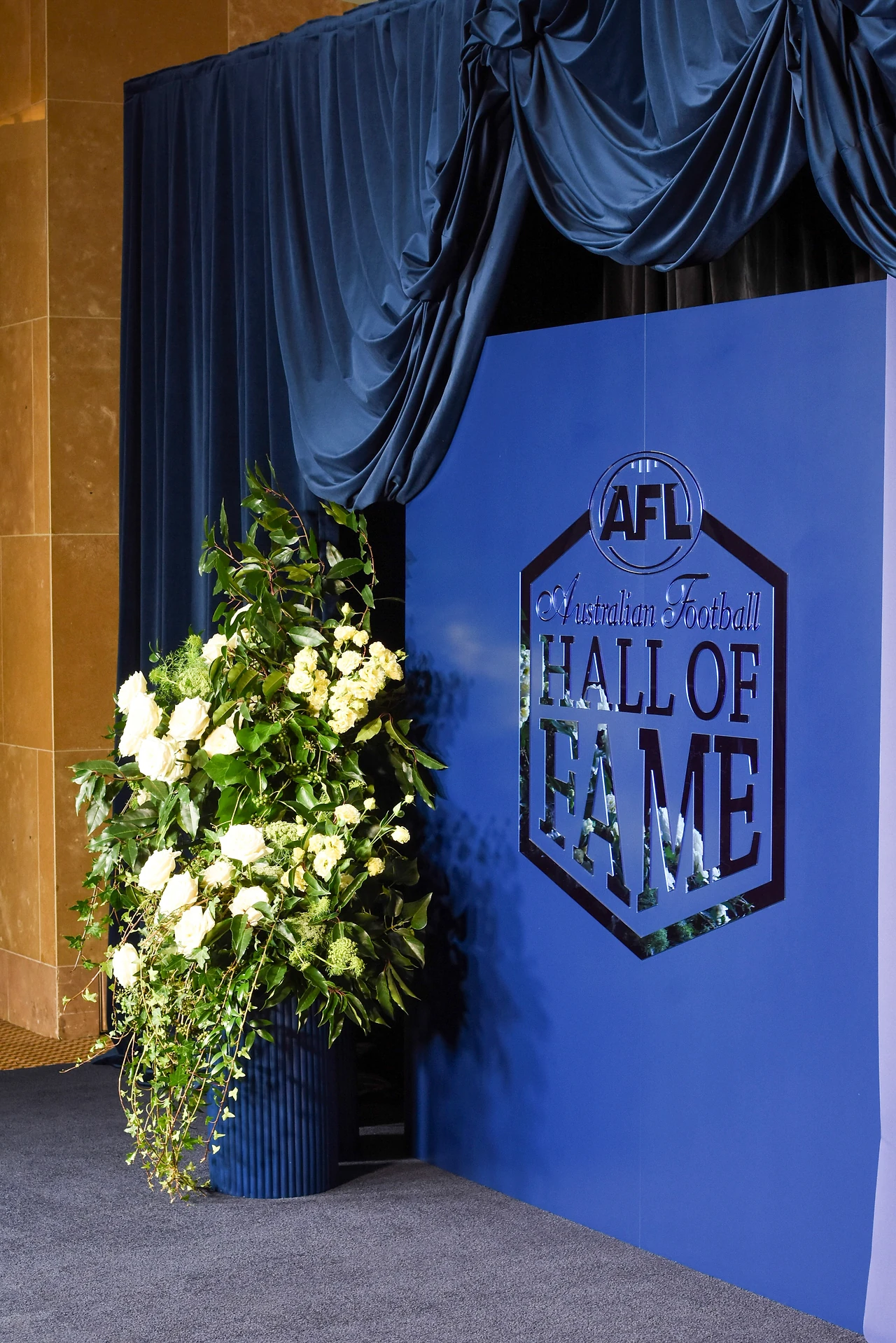 Close view of gathered navy velvet swags above the AFL Hall of Fame logo wall