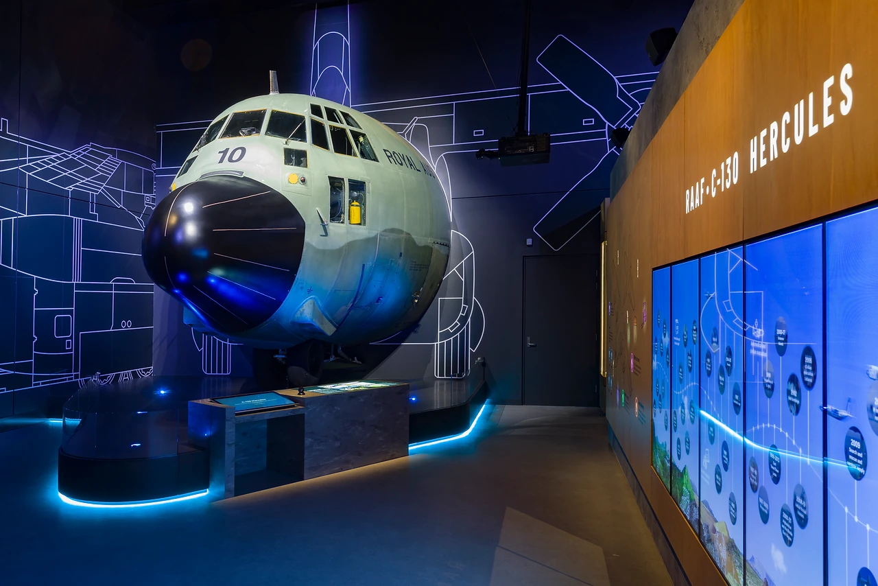 C-130 Hercules nose section on a lit plinth with blueprint-style wall graphics
