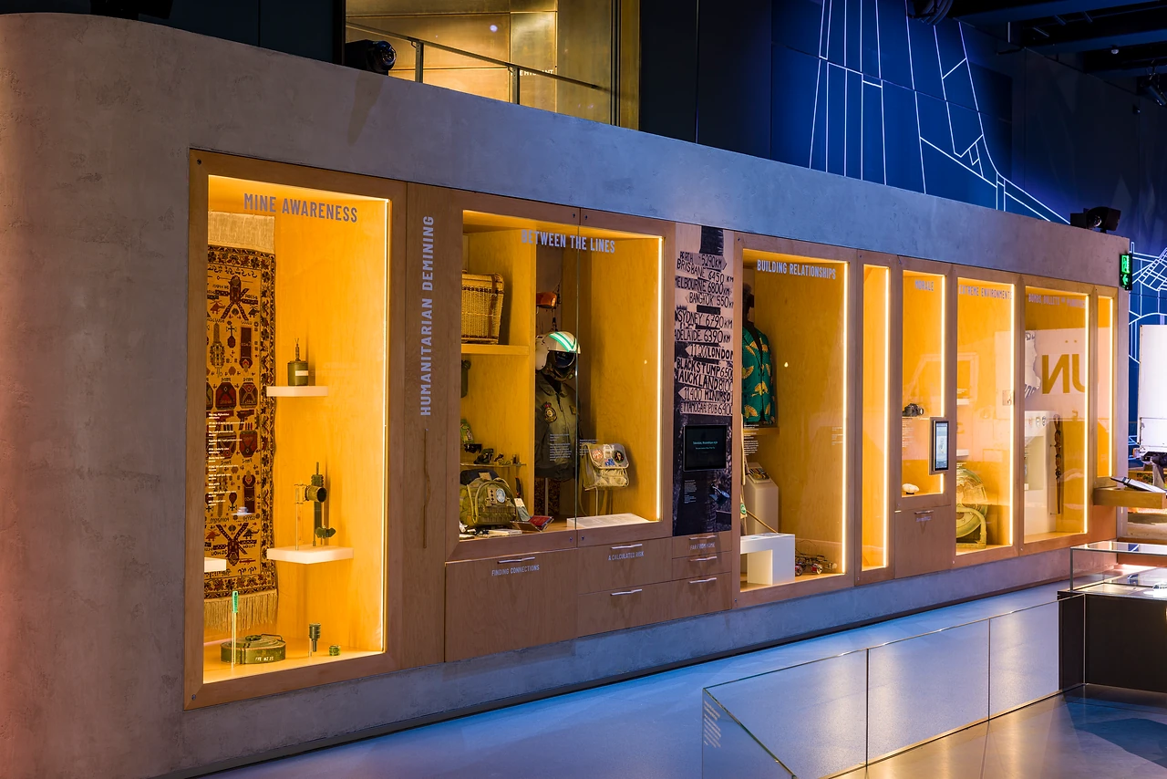 Backlit amber alcove showcases holding textiles and personal objects