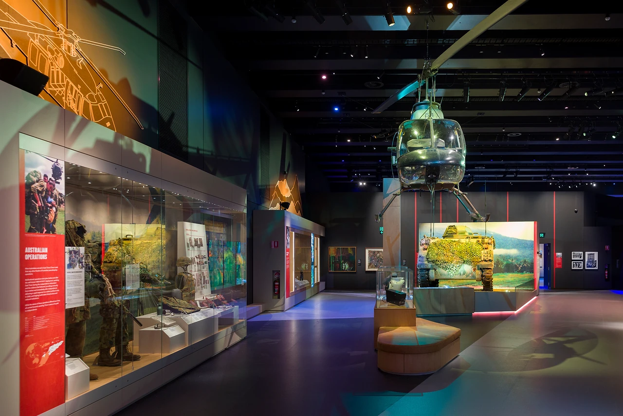 Gallery interior with a helicopter suspended above showcases and a vehicle diorama