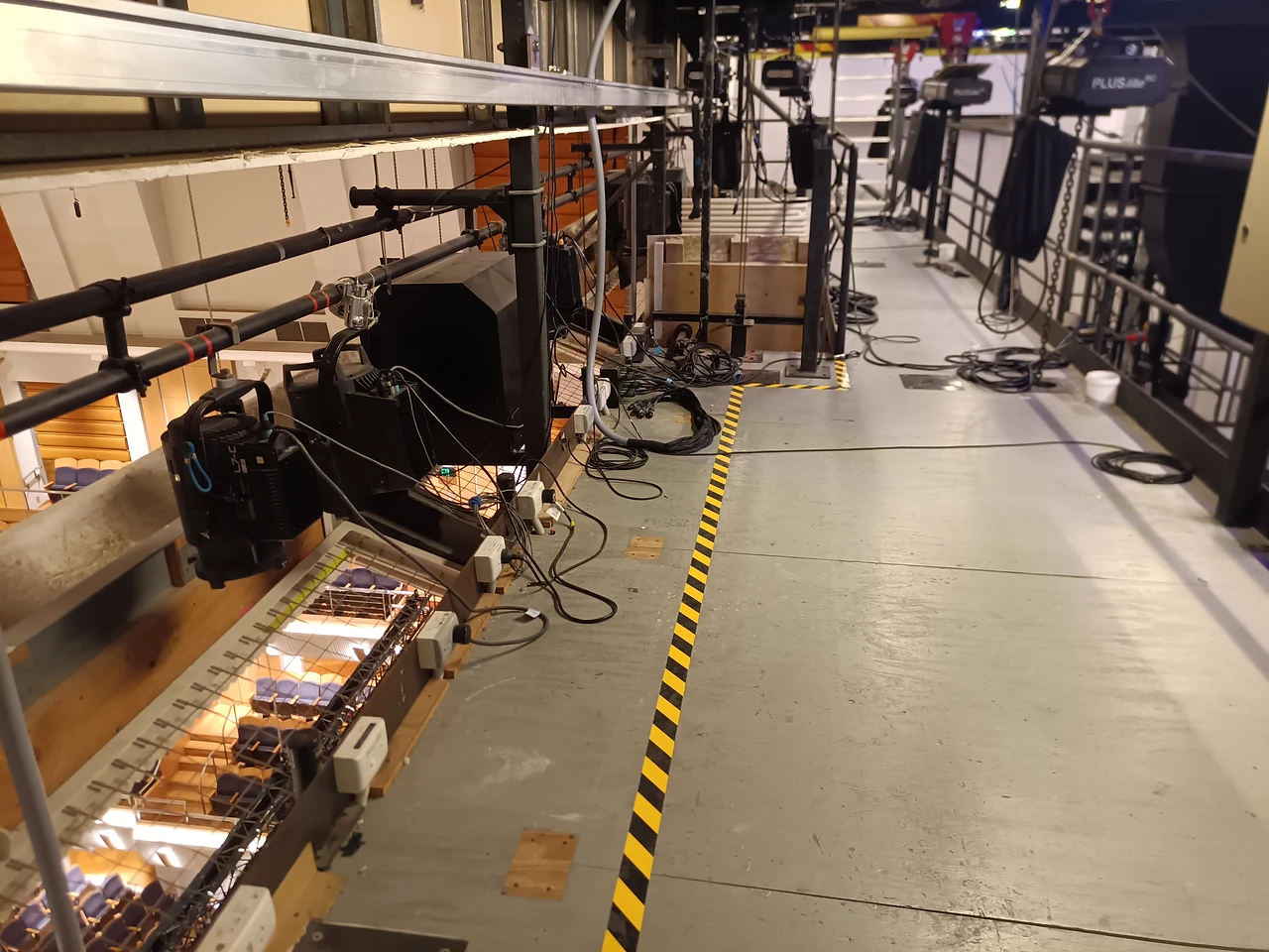 Lighting bridge walkway with hoisted speaker boxes beside the balcony rail