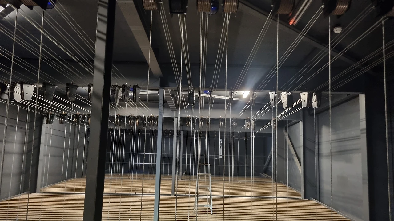 Fly loft with head blocks and wire lines above the stage grid and timber floor