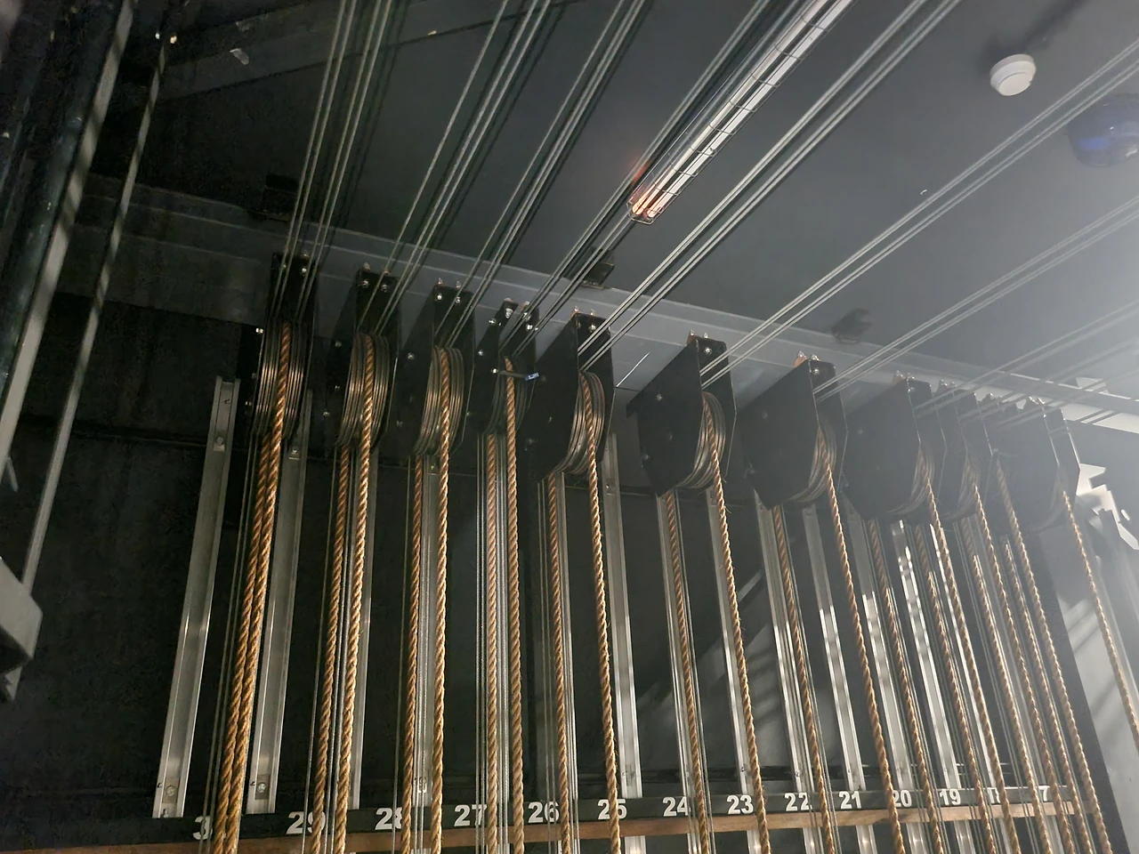 Row of head block sheaves with rope runs dropping to the counterweight guides below