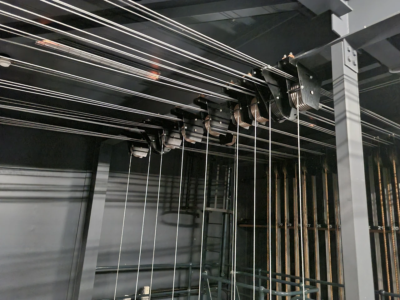 Head block sheaves mounted on steel beams with wire lines running across the loft