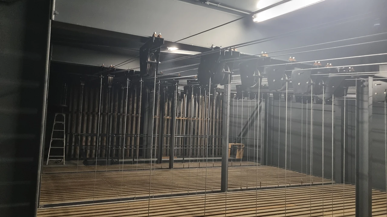 Fly loft grid with a ladder, head blocks and wire lines fanning to the stage below