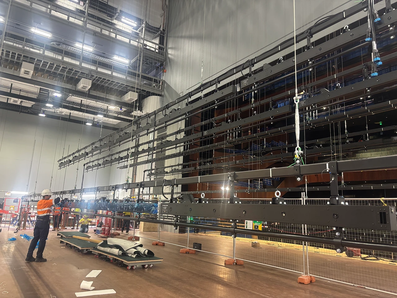 Row of ILX lighting bars suspended over the stage with a technician working beneath