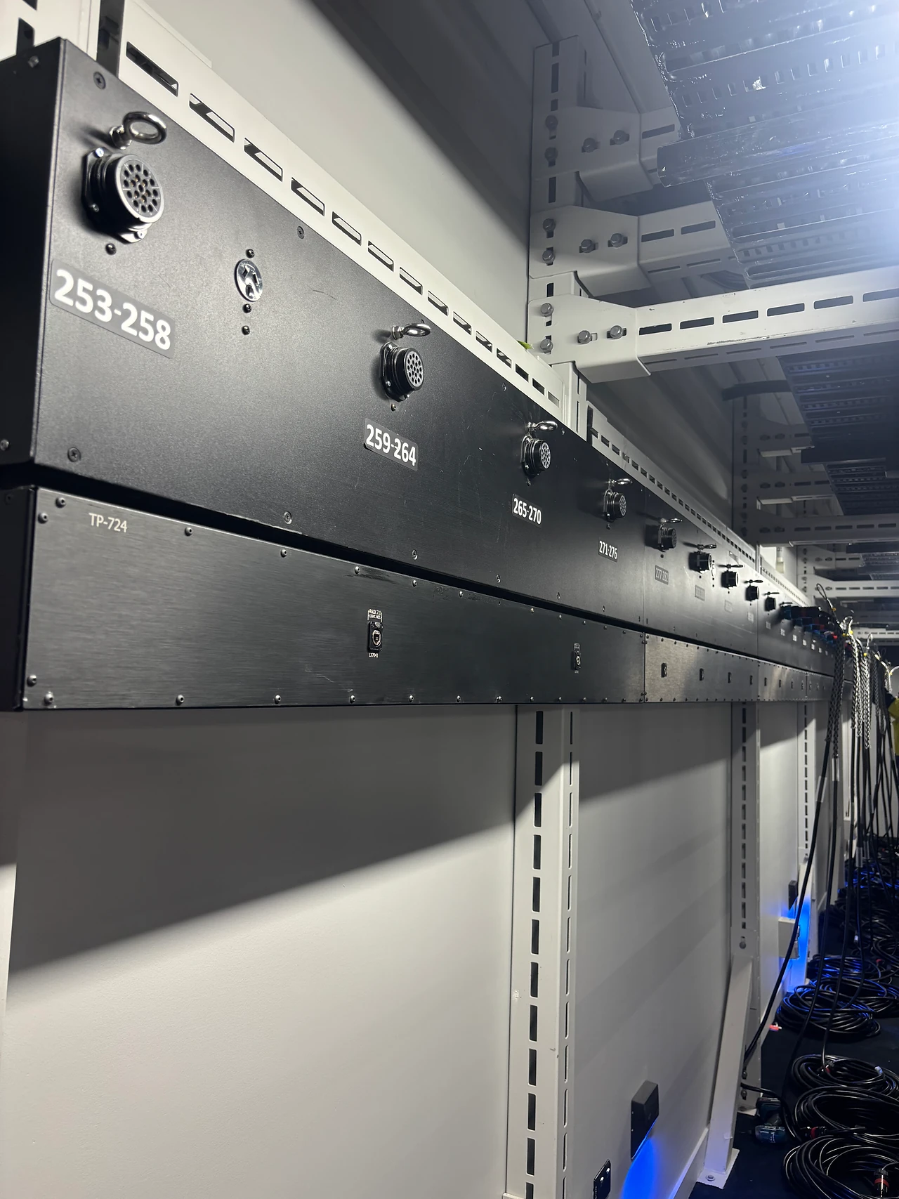 Numbered black plug box panel on a technical gallery wall with cable bundles below