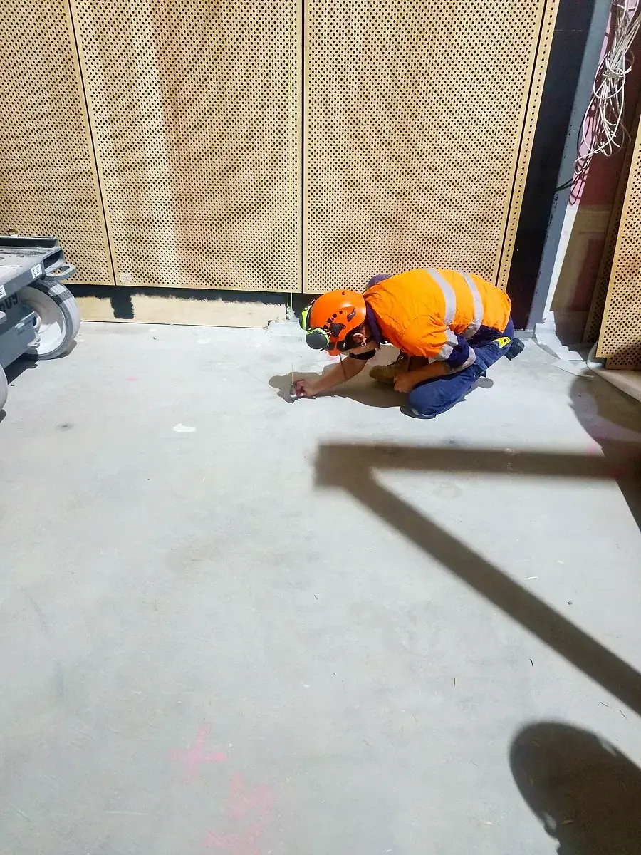 Crew member marking out fixing points on the studio floor.