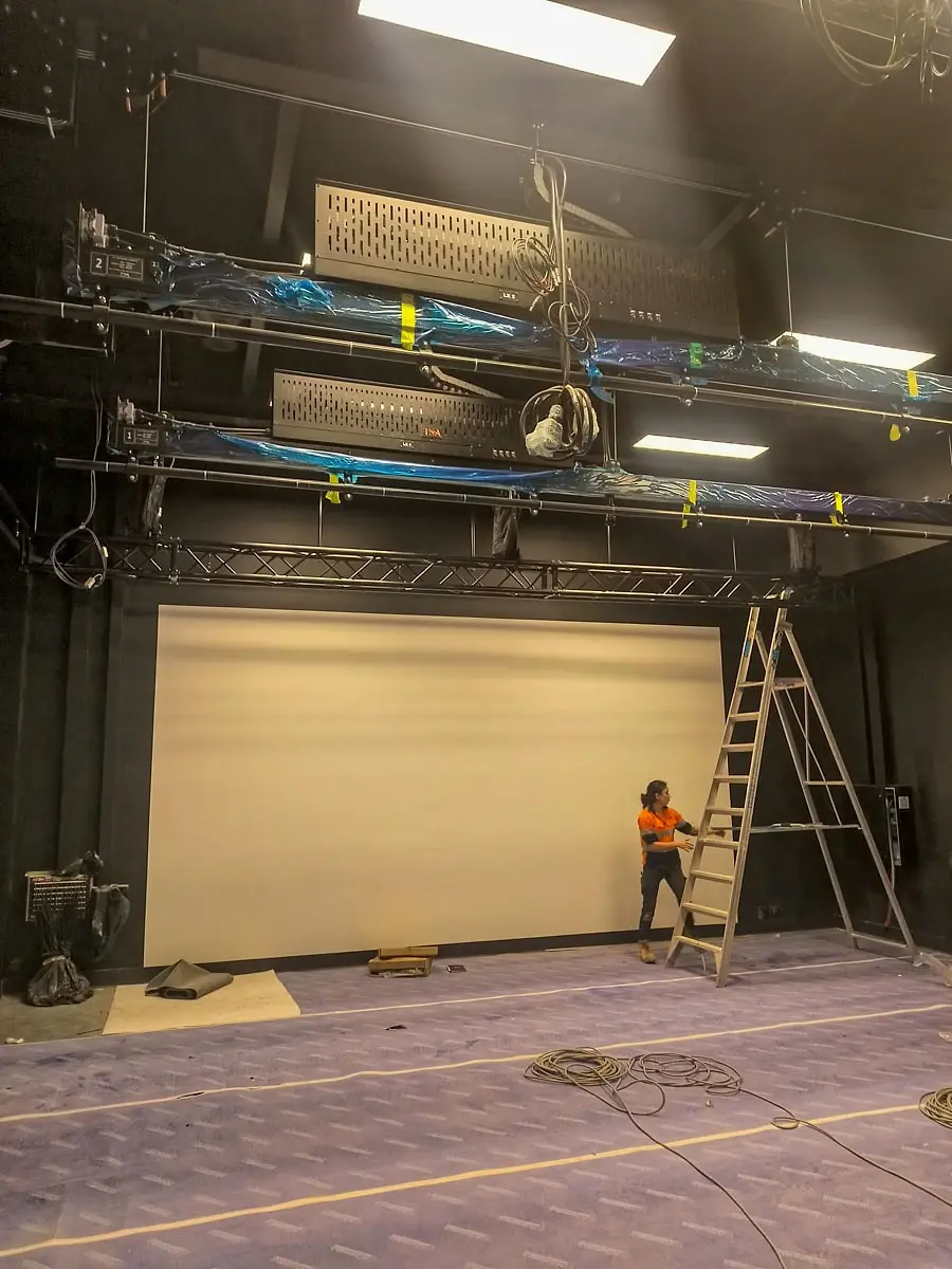 Two crew members installing a lighting grid together in the new studio space.