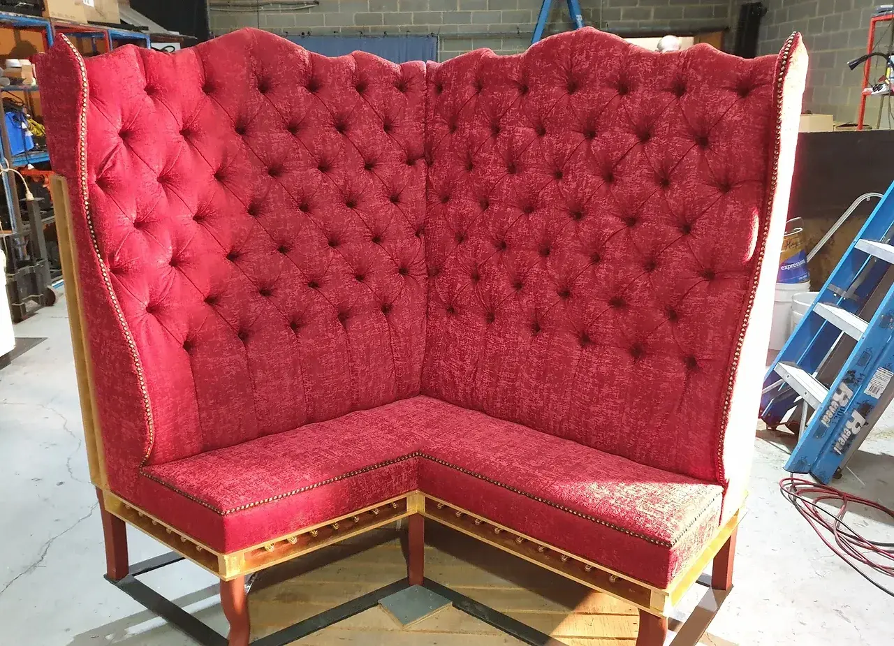 Custom red velvet corner banquette built for Moulin Rouge, finished from a driveway workshop during lockdown. Photo: Reveal Productions.