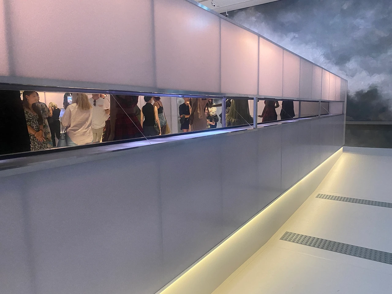 Long gallery corridor with a lit slot window and a cloud-painted wall above