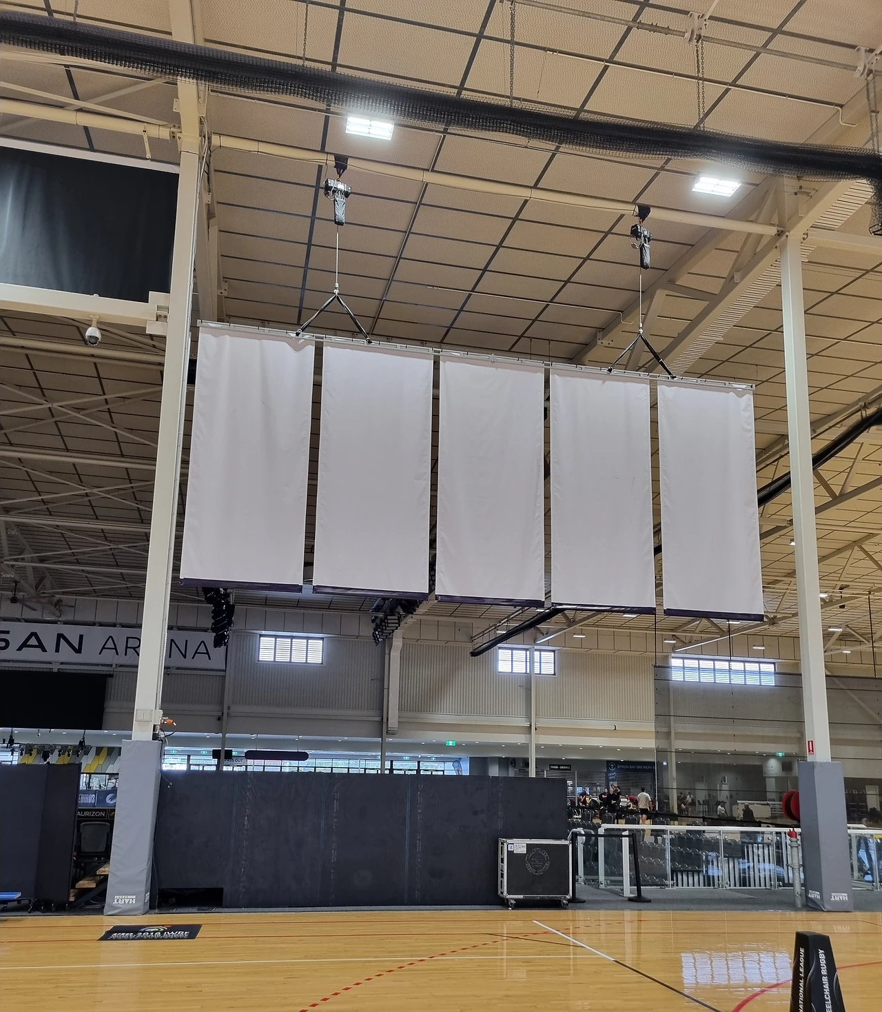 White drapes hung from the roof steel above the arena court at mezzanine height