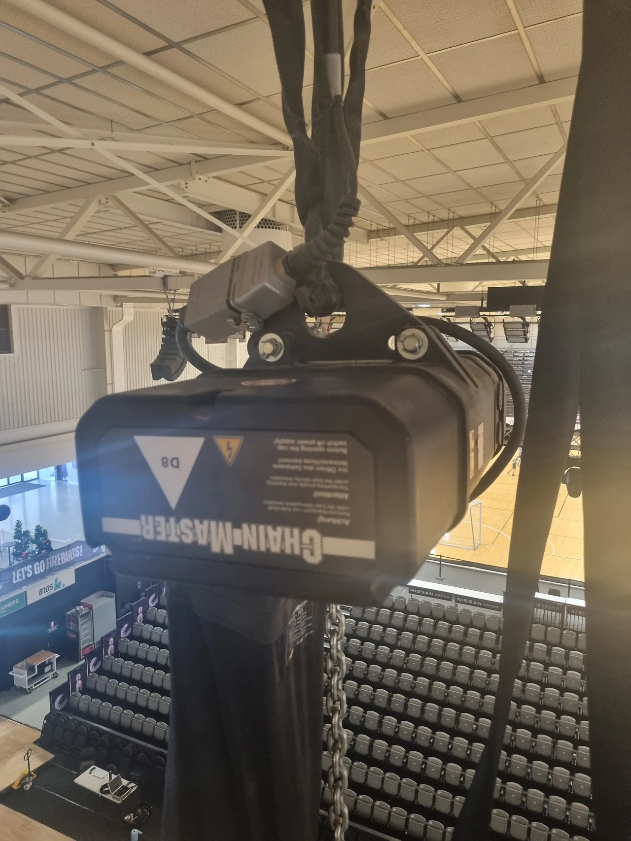 Chain hoist hanging from a rigging point above the arena seating bowl