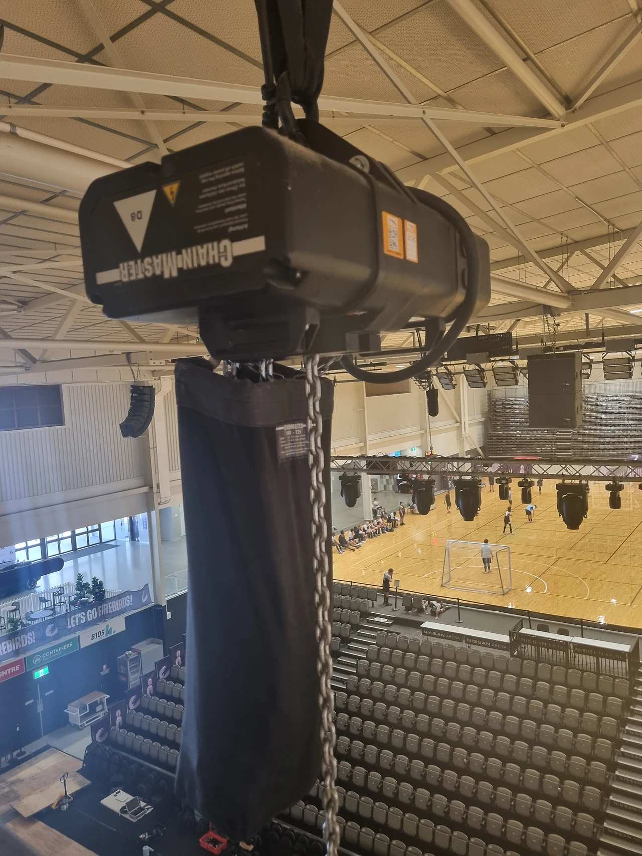Electric chain hoist with load chain bag suspended over the court