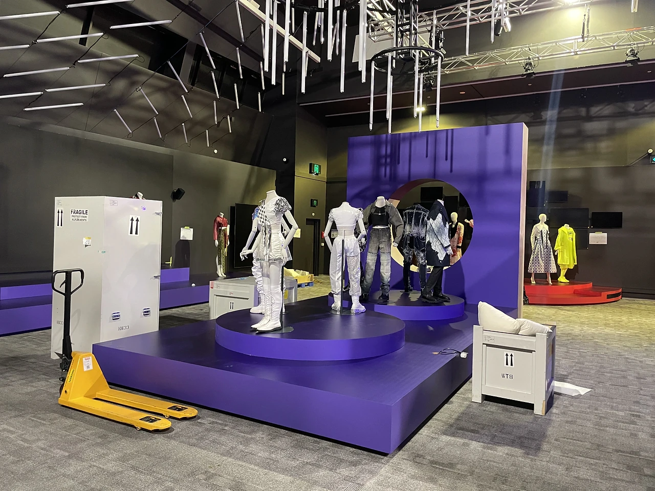 Purple circular podium with mannequins in silver and white stage outfits