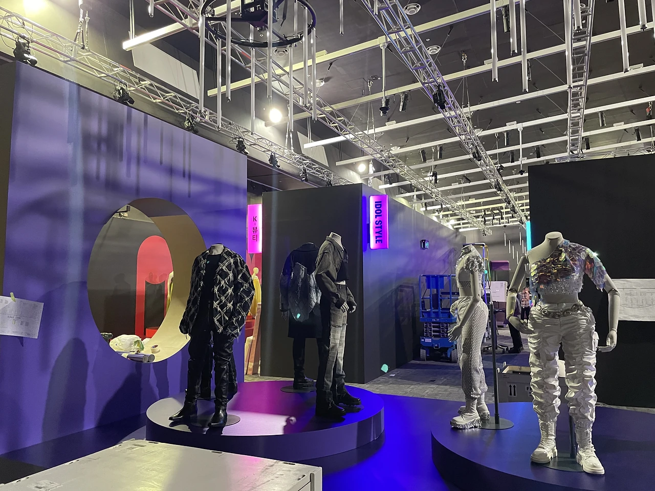 Mannequins on lit blue circular plinths in front of a purple wall with circular cut-out