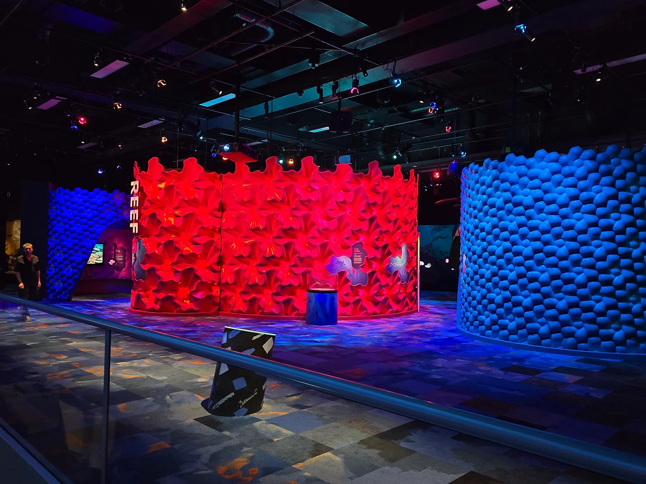 Wall of red sculpted coral polyps lit for the Reef zone, with a blue faceted wall beside it. Design: Museums Victoria design department. Photo: Tim Blaikie.