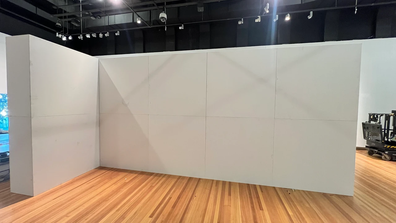 Corner of the white modular gallery wall during the install, before finishing, with the track lights overhead at the State Library of Queensland. Design: Tim Blaikie, TSA. Photo: TSA.