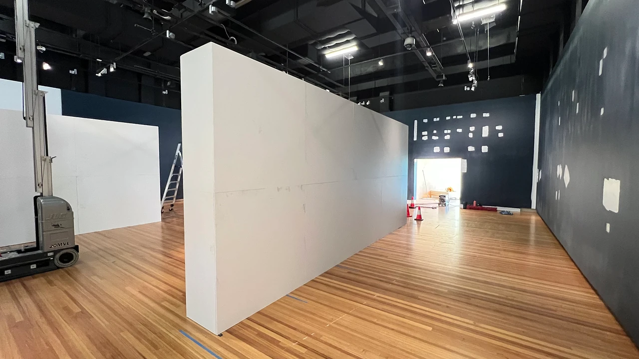Long white wall run in an empty exhibition hall with a dark blue back wall and timber floor, before the artworks go up. Design: Tim Blaikie, TSA. Photo: TSA.