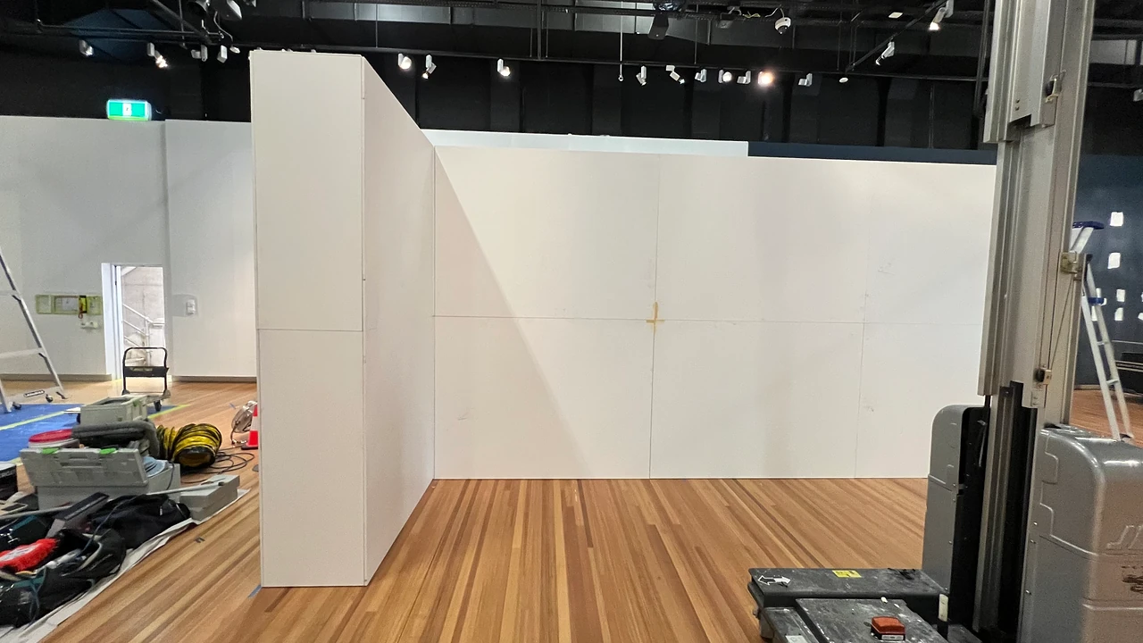 Modular wall panels standing in the gallery as the corner return is assembled, with a lift and tool cases alongside. Design: Tim Blaikie, TSA. Photo: TSA.