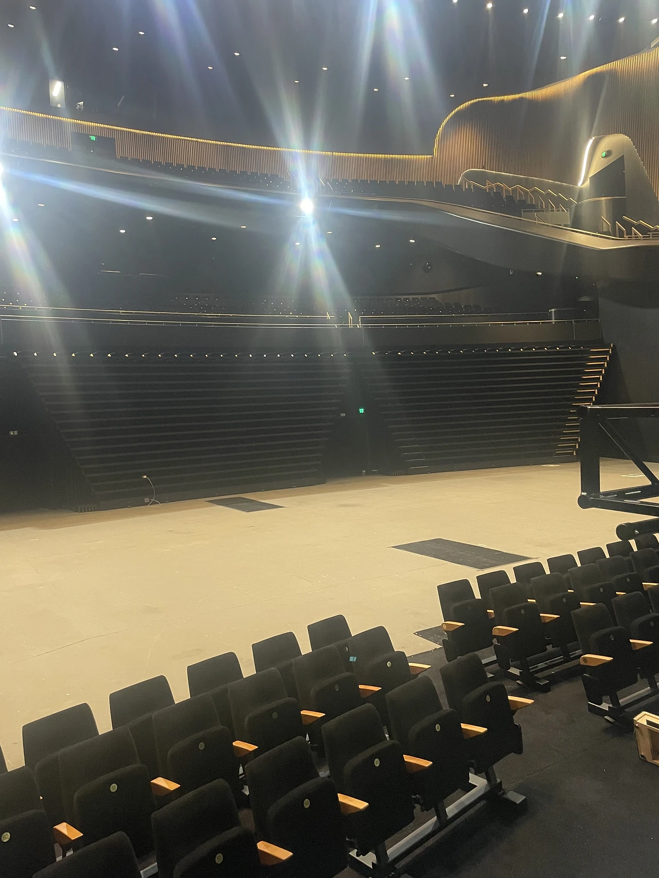 Front rows of the seating bank set out on the stage floor under work lights