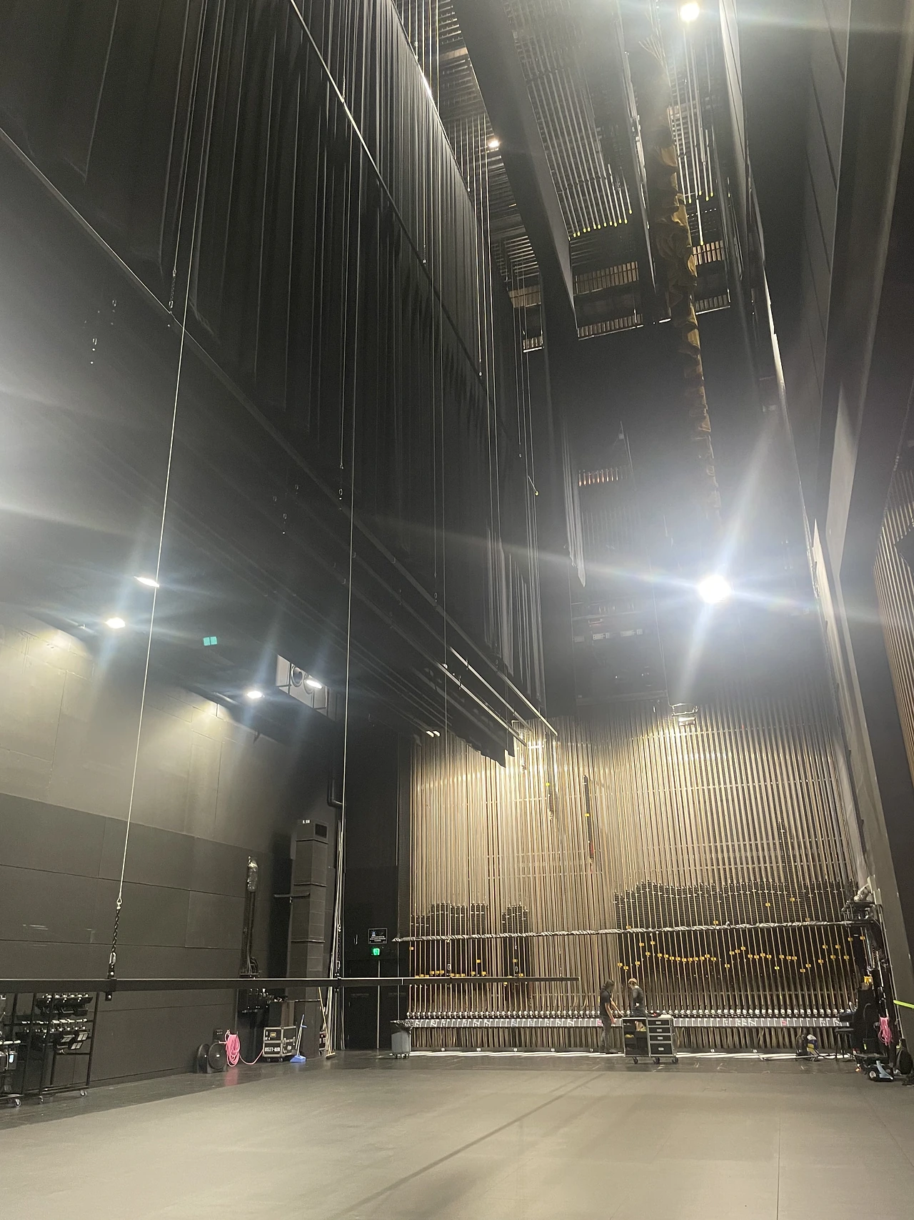 Tall stage house with hanging lines and a lit proscenium opening at the far end