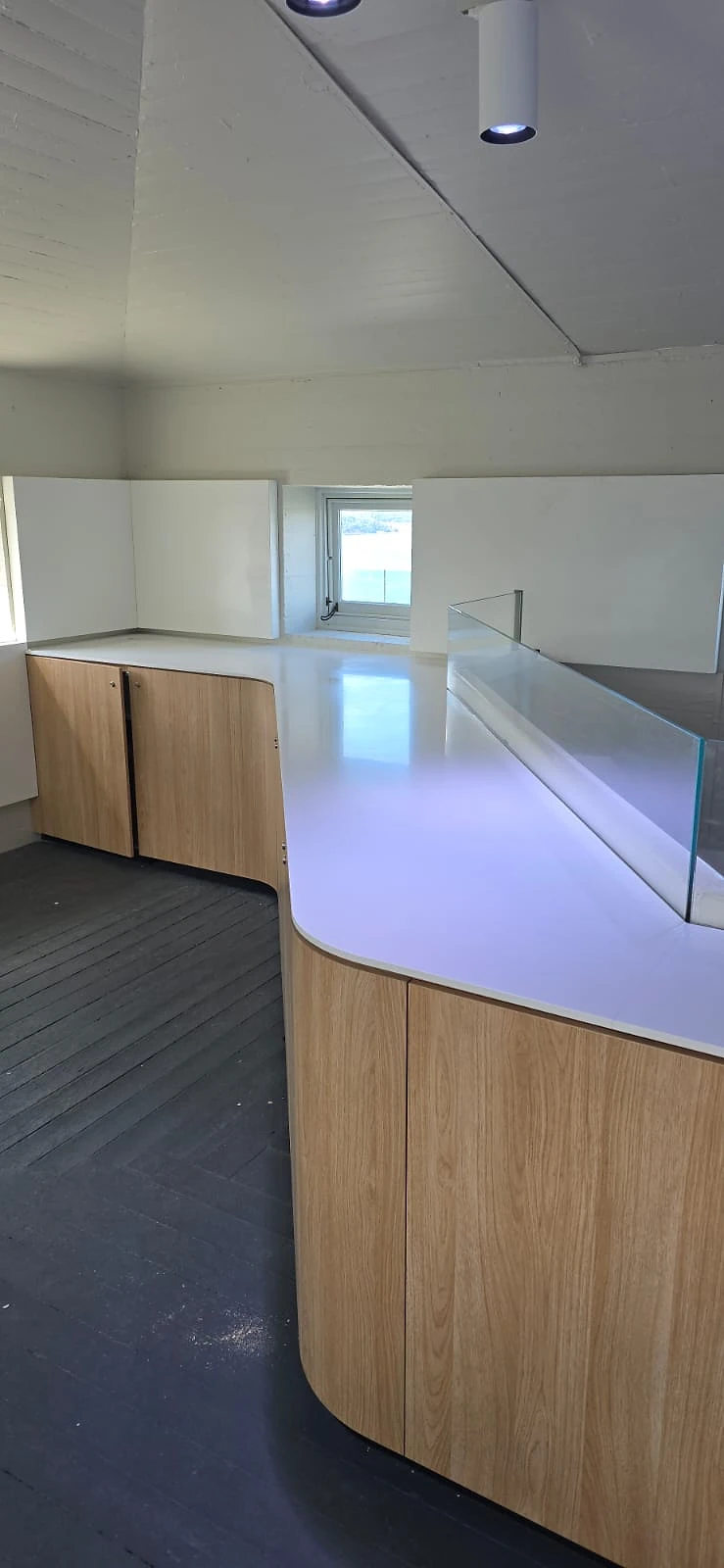 Timber and white solid-surface counter curving along a pylon room window wall