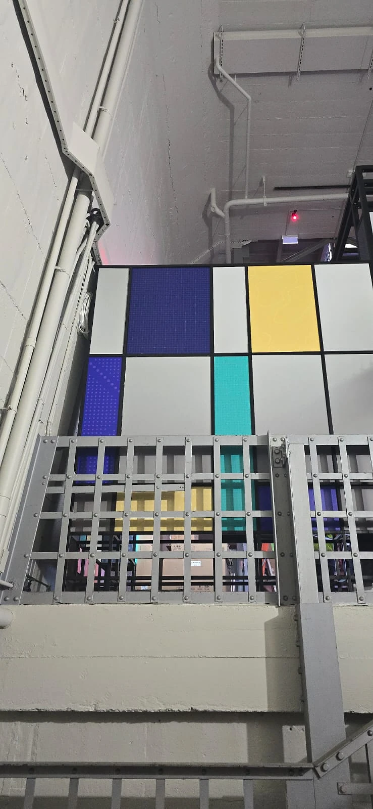 Colour-blocked graphic wall above a grey steel grille balustrade