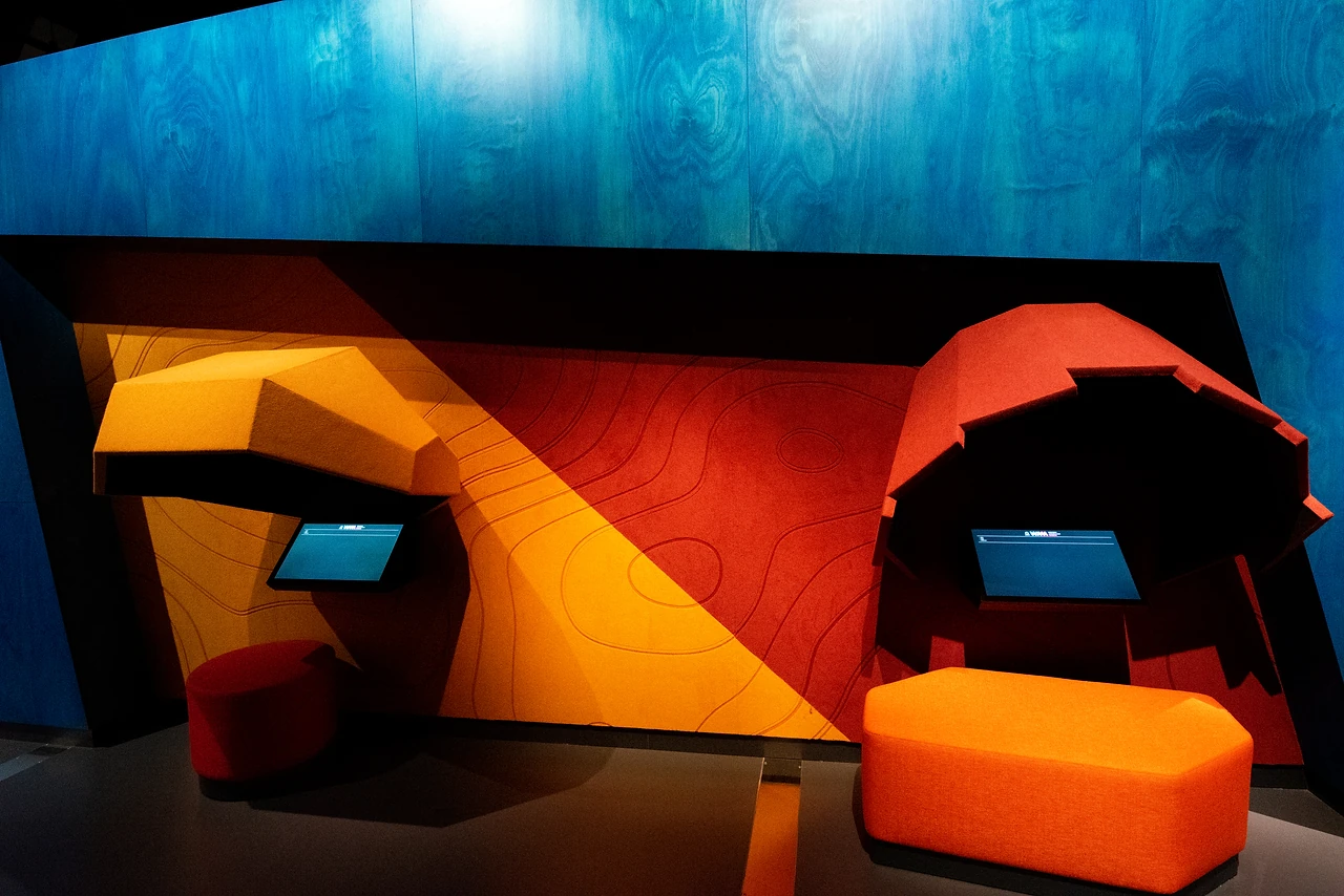 Angular timber and orange upholstered seating nook against a blue wall in the Changes gallery. Design: Freeman Ryan Design. Photo: Michelle Sammut.