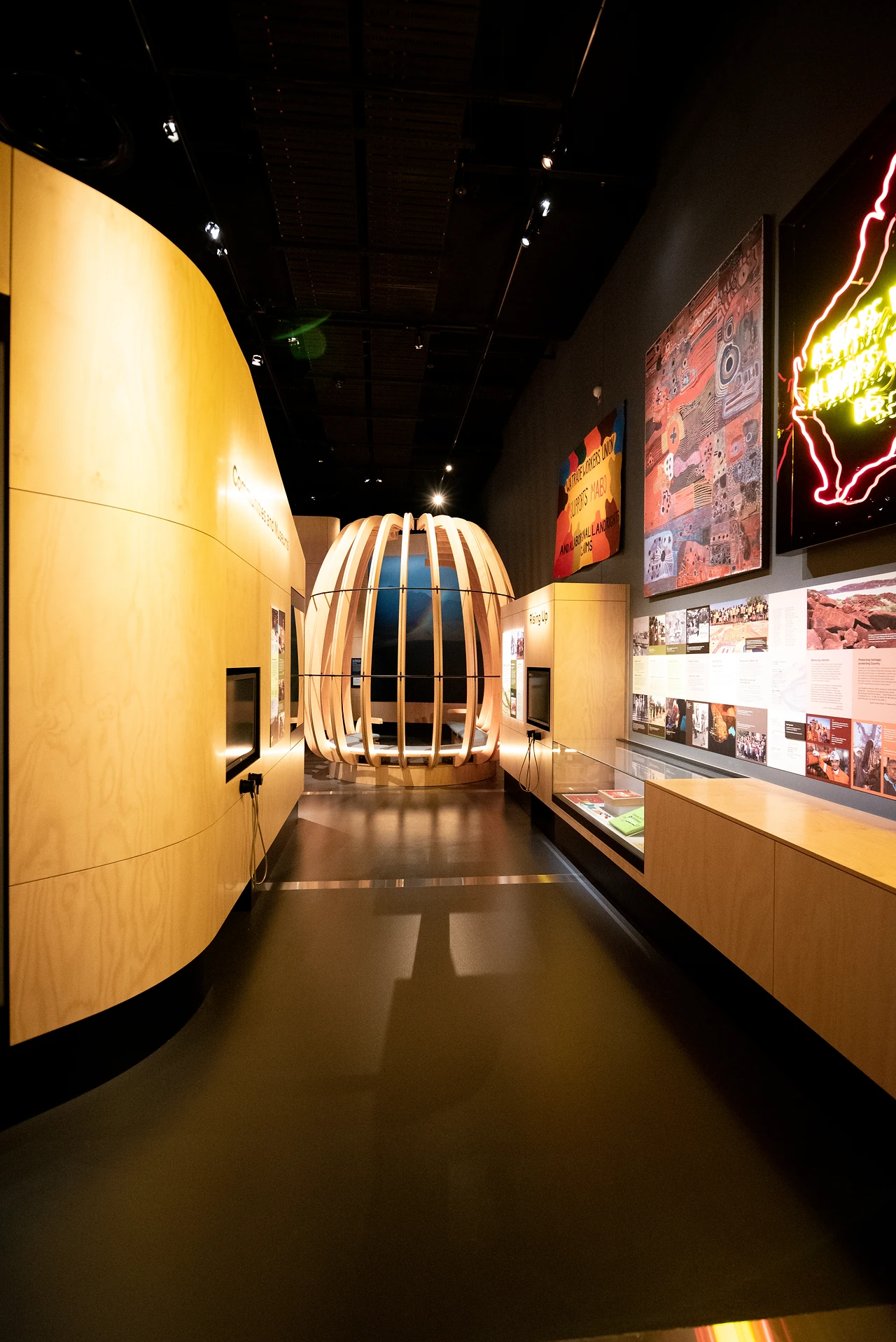 Narrow Ngalang Koort Boodja Wirn gallery corridor with a timber rib pod ahead and a joinery wall with showcases to the right. Design: Thylacine Design with Iredale Pedersen Hook architects. Photo: Michelle Sammut.