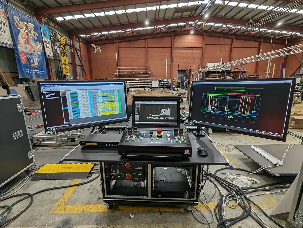 TSA's Raynok show-control desk set up in the workshop, three screens running cue data and a 3D stage visualiser above the console.