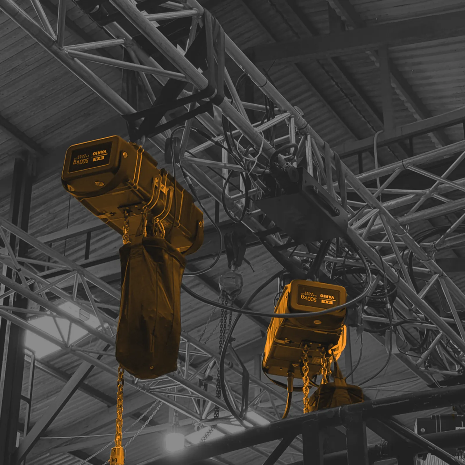Grouped chain hoists and box truss installed overhead in a venue