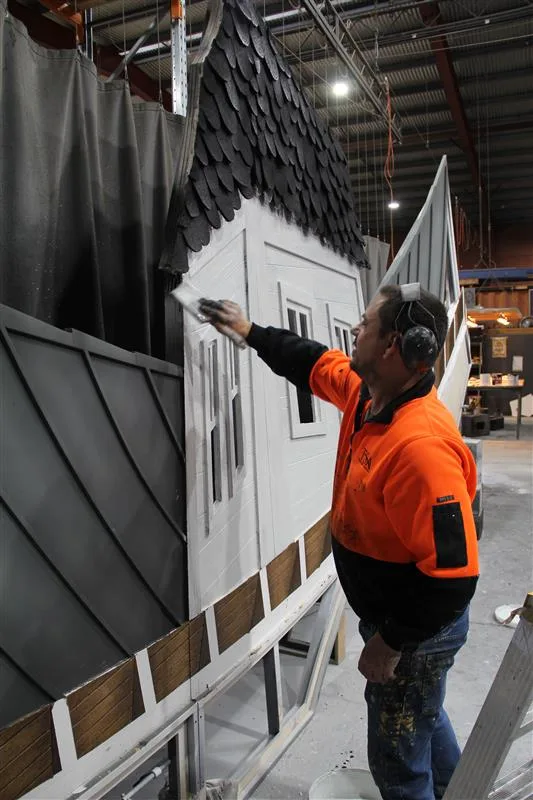 A scenic artist painting the Beetlejuice the Musical house facade set piece